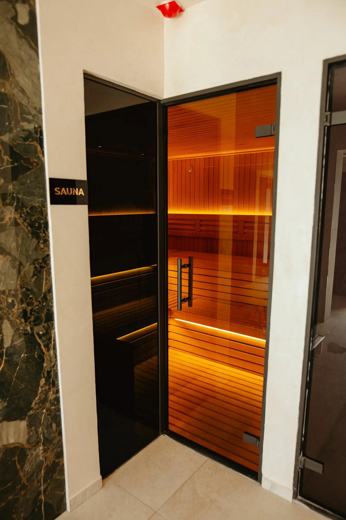 Otvorena staklena vrata saune sa natpisom Sauna