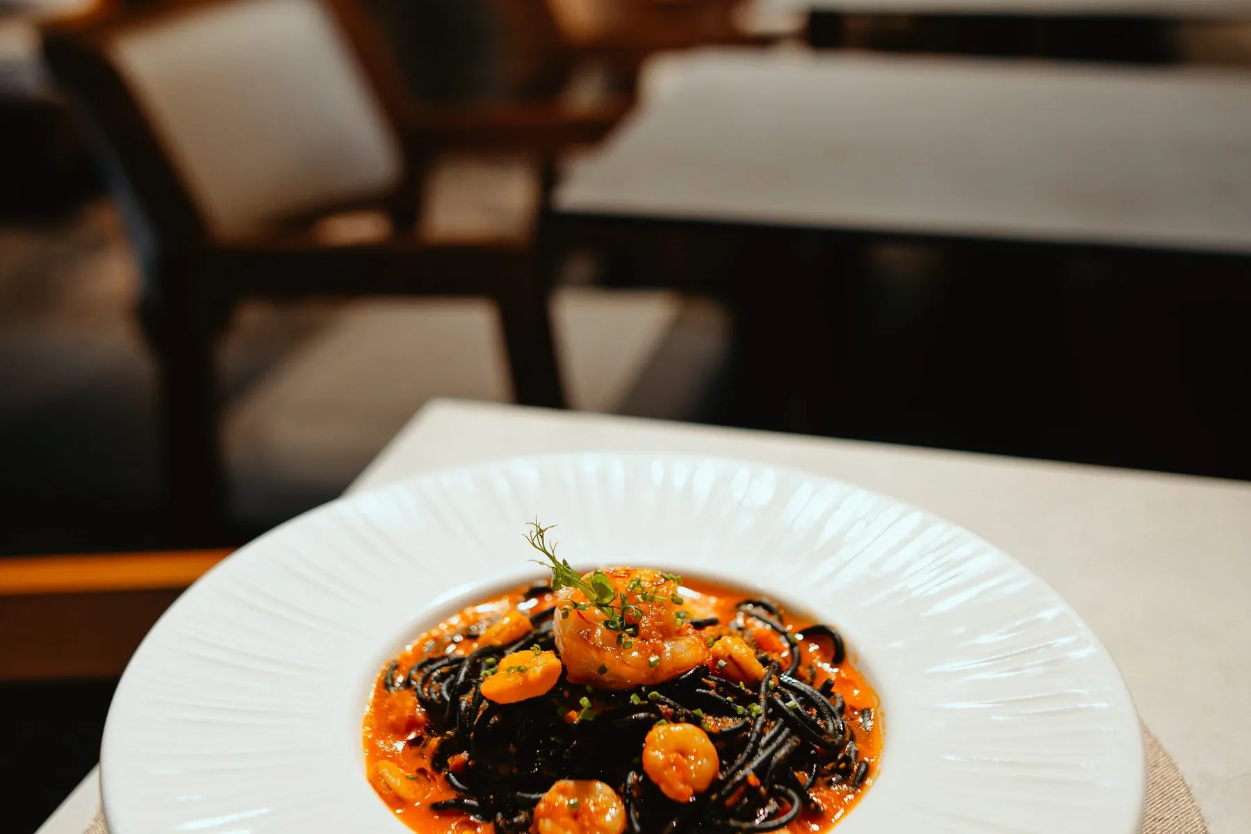 Crna pasta sa škampima, sto u sali restorana