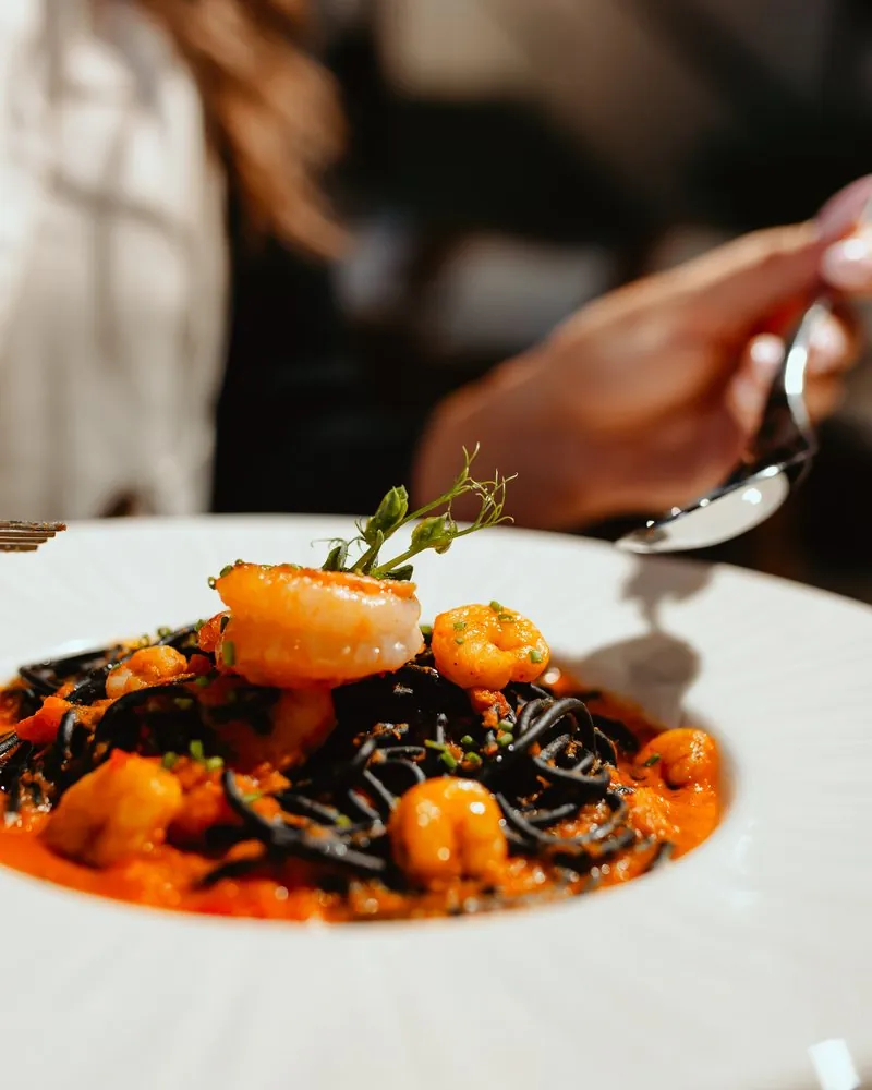 Crna pasta sa škampima na belom tanjiru